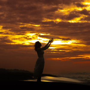 woman with arms reaching to the sky in gratitude