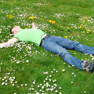 man laying on daisy covered grass relaxing