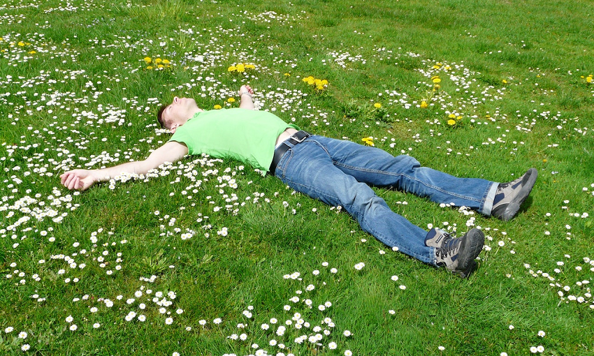 man laying on daisy covered grass relaxing