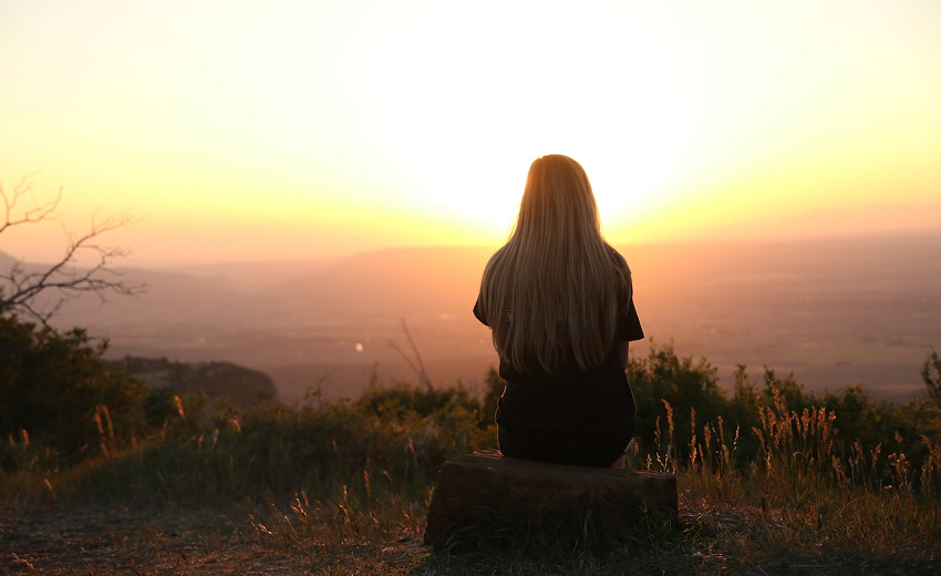 woman sitting outside watching sun rise