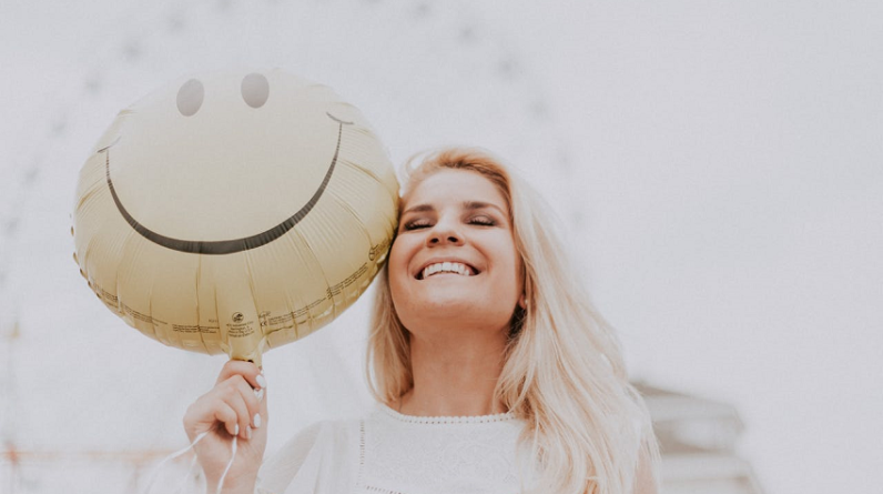 happy woman holding smiley face balloon