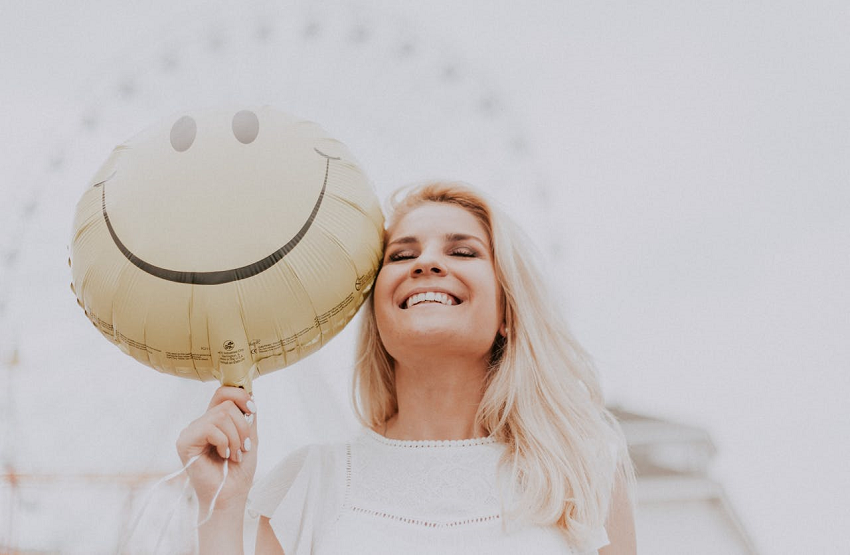 happy woman holding smiley face balloon