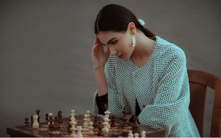 woman playing chess and thinking hard