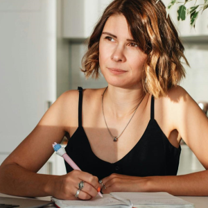 woman writing in a journal and thinking seriously