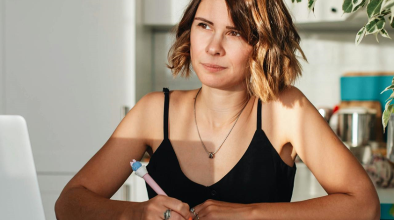 woman writing in a journal and thinking seriously