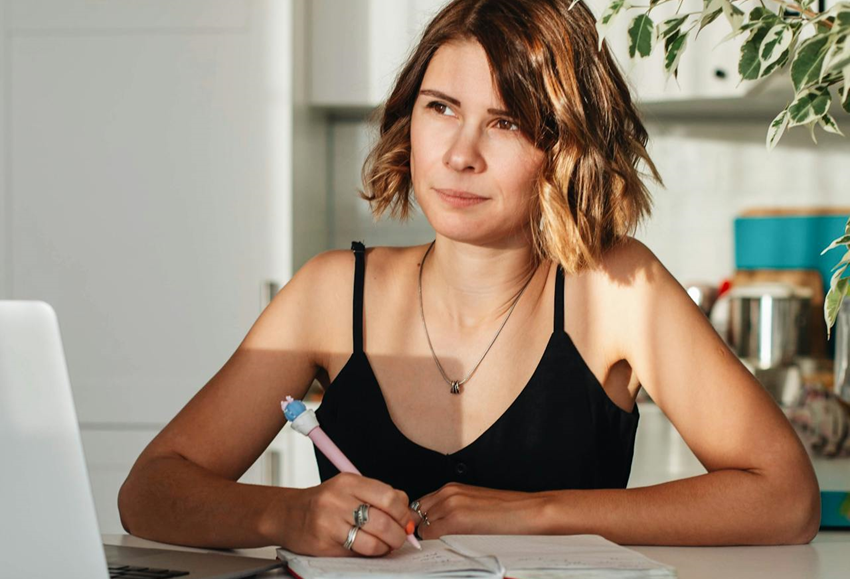 woman writing in a journal and thinking seriously