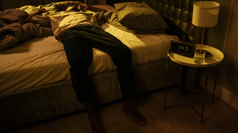 man laying sideways on bed struggling with insomnia