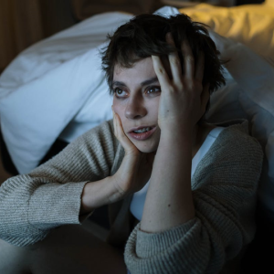 woman with insomnia sitting on the floor next to her bed