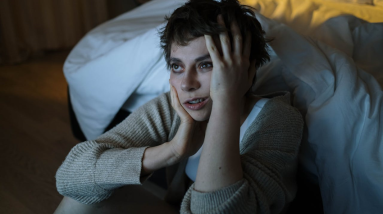 woman with insomnia sitting on the floor next to her bed