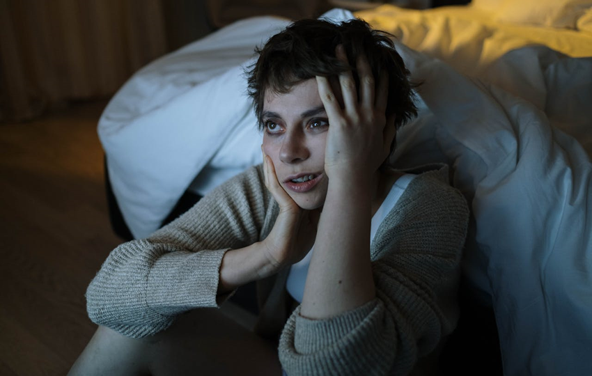 woman with insomnia sitting on the floor next to her bed