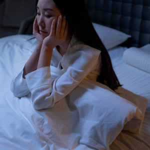 woman struggling with insomnia sitting up in bed at night