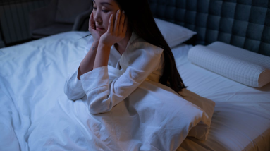 woman struggling with insomnia sitting up in bed at night