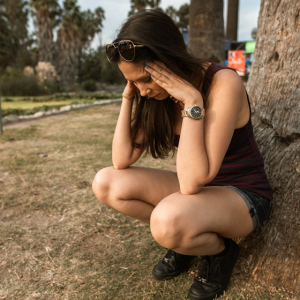 woman crouching down next to tree looking worried and anxious