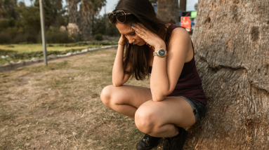 woman crouching down next to tree looking worried and anxious