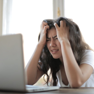 woman looking very stressed while looking at her laptop