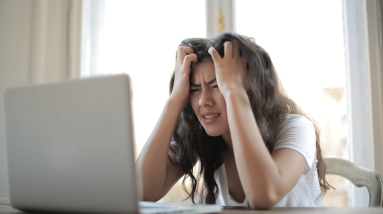 woman looking very stressed while looking at her laptop