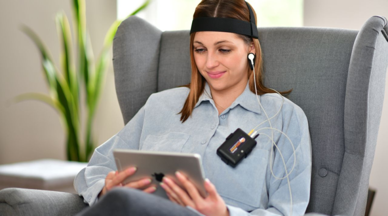 Woman using neurofeedback device sitting in armchair
